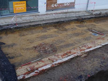Opgraving De Vrijheid - kerkhof met afzonderlijke grafkuilen (bruin) uitgegraven in de natuurlijke bodem (geel), op de voorgrond is de bakstenen kerkhofmuur zichtbaar (Sint-Martensstraat) - copyright Solva